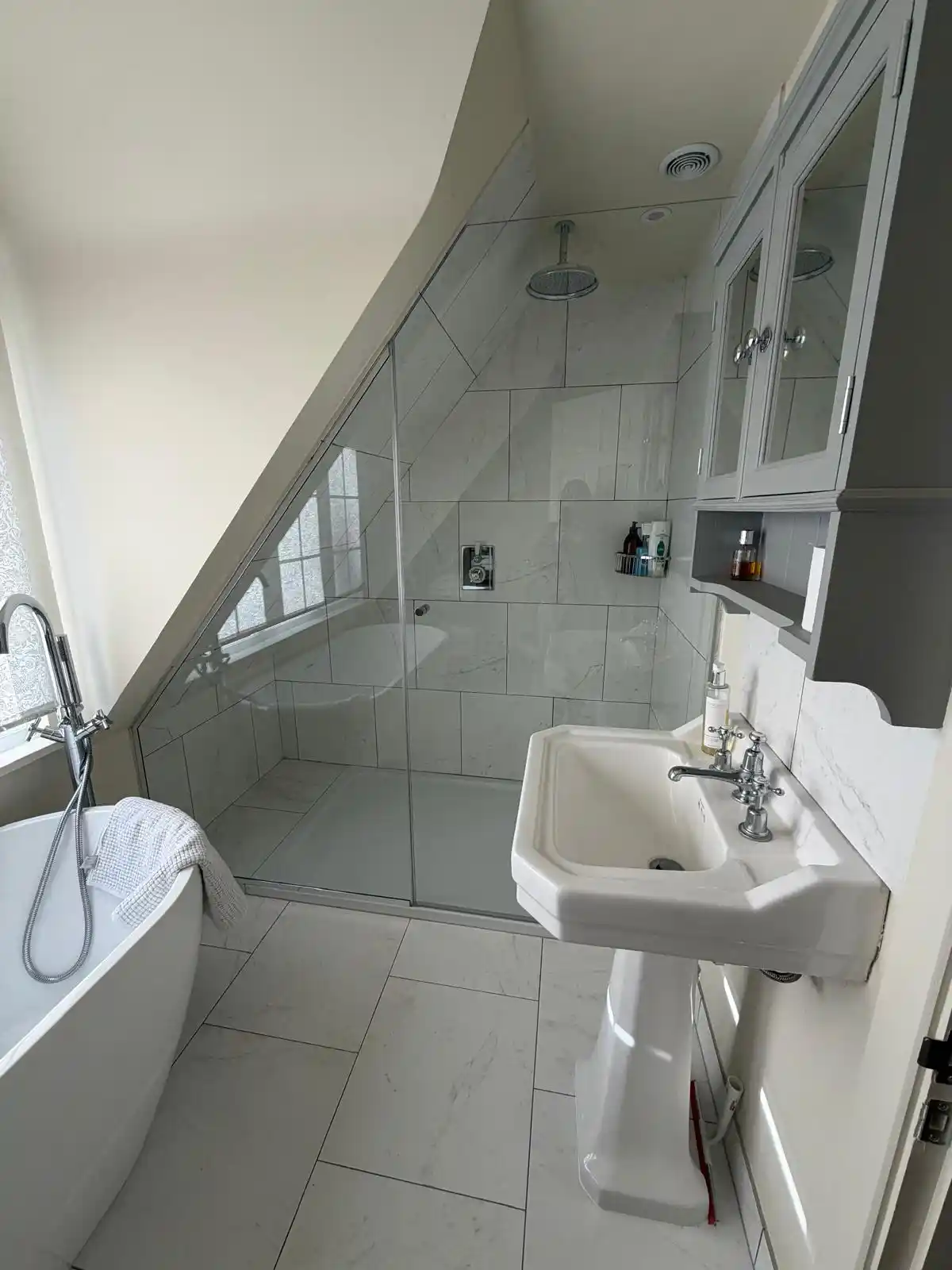 Bespoke glass shower screen fitted under eaves by Bucks Glazing