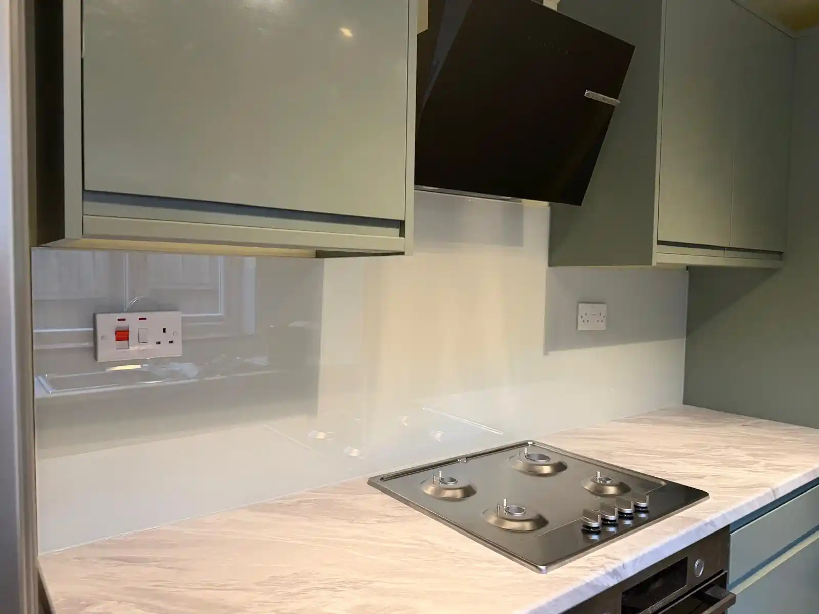 White glass kitchen splashback behind hob by Bucks Glazing